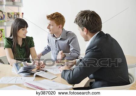 Stock Image - Real estate agent discussing property documents to his clients. Fotosearch