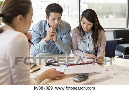 Stock Photo - Real estate agent discussing property documents to his clients. Fotosearch