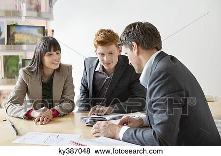 Stock Photo - Real estate agent discussing property documents to his clients. Fotosearch