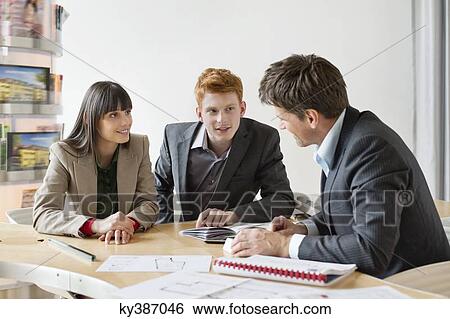 Real estate agent discussing property documents to his clients View Large Photo Image Stock Photograph - Real estate agent discussing property documents to his clients. Fotosearch