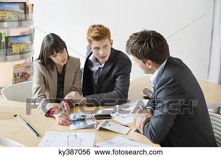 Stock Photograph - Real estate agent discussing property documents to his clients. Fotosearch
