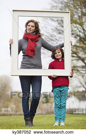 Woman and her son holding a picture frame in a park View Large Photo Image Stock Image - Woman and her son holding a picture frame in a park. Fotosearch