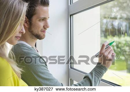 Stock Photo - Woman looking at an architect drawing a design on the window glass. Fotosearch