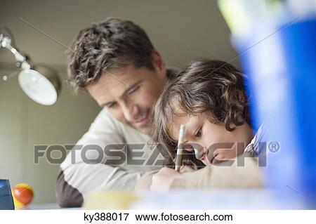 Boy studying with his father at home View Large Photo Image Stock Photo - Boy studying with his father at home. Fotosearch