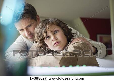 Boy thinking while studying with his father at home View Large Photo Image Stock Photo - Boy thinking while studying with his father at home. Fotosearch