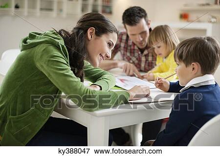 Couple teaching their children at home View Large Photo Image Stock Photo - Couple teaching their children at home. Fotosearch