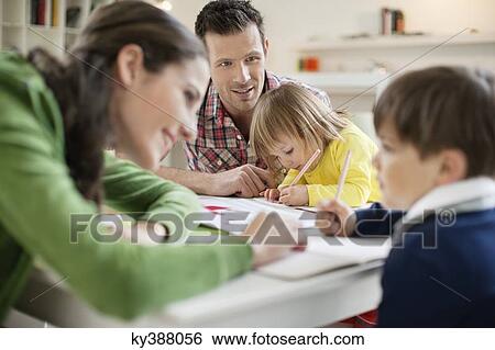 Couple teaching their children at home View Large Photo Image Stock Photograph - Couple teaching their children at home. Fotosearch