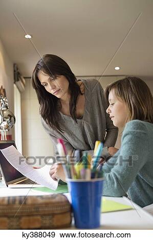 Stock Photo - Girl studying with her mother at home. Fotosearch