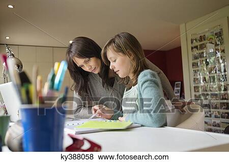 Stock Photo - Girl studying with her mother at home. Fotosearch