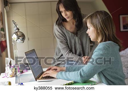 Girl studying with her mother on a laptop at home View Large Photo Image Stock Photography - Girl studying with her mother on a laptop at home. Fotosearch