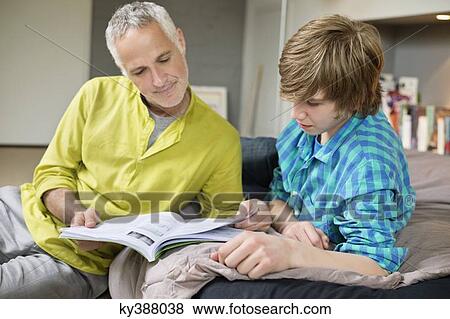 Stock Photo - Teenage boy studying with his father at home. Fotosearch