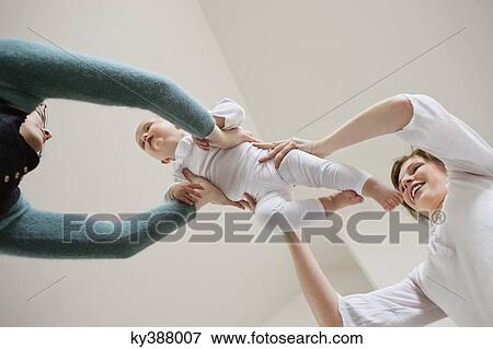 Stock Photo - Woman giving her baby to another woman. Fotosearch