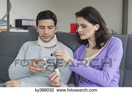 Woman giving medicine to her husband suffering from neckache View Large Photo Image Stock Image - Woman giving medicine to her husband suffering from neckache. Fotosearch