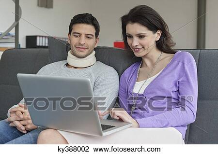 Woman using a laptop with her husband beside her View Large Photo Image Stock Image - Woman using a laptop with her husband beside her. Fotosearch