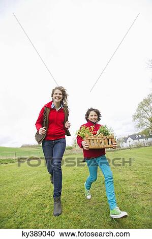 Boy carrying a basket of assorted vegetables with his mother in a farm View Large Photo Image Stock Image - Boy carrying a basket of assorted vegetables with his mother in a farm. Fotosearch