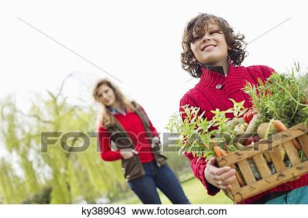 Boy holding a crate of assorted vegetables with his mother in a farm View Large Photo Image Stock Image - Boy holding a crate of assorted vegetables with his mother in a farm. Fotosearch