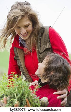 Boy holding a crate of assorted vegetables with his mother in a farm View Large Photo Image Stock Image - Boy holding a crate of assorted vegetables with his mother in a farm. Fotosearch