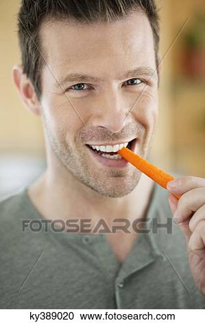 Man eating a carrot View Large Photo Image Stock Image - Man eating a carrot. Fotosearch