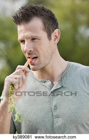 Man eating a carrot View Large Photo Image Stock Image - Man eating a carrot. Fotosearch