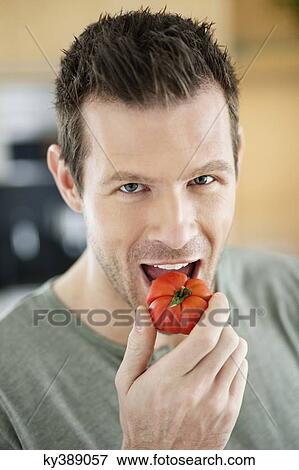 Man eating a tomato View Large Photo Image Stock Photo - Man eating a tomato. Fotosearch