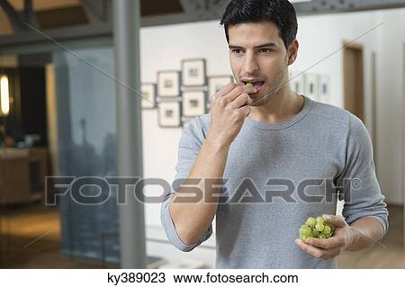 Man eating grapes View Large Photo Image Stock Image - Man eating grapes. Fotosearch