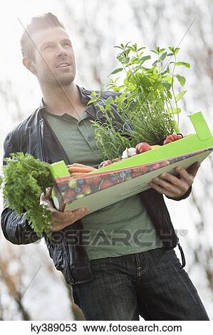 Man holding a tray of raw vegetables View Large Photo Image Stock Image - Man holding a tray of raw vegetables. Fotosearch