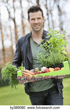 Man holding a tray of raw vegetables View Large Photo Image Stock Image - Man holding a tray of raw vegetables. Fotosearch
