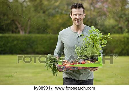 Stock Photo - Man holding a tray of raw vegetables. Fotosearch