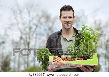 Man holding a tray of raw vegetables View Large Photo Image Stock Photo - Man holding a tray of raw vegetables. Fotosearch