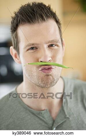 Man making artificial mustache with green bean View Large Photo Image Stock Photograph - Man making artificial mustache with green bean. Fotosearch