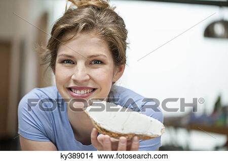 Portrait of a woman eating toast with cream spread on it View Large Photo Image Picture - Portrait of a woman eating toast with cream spread on it. Fotosearch