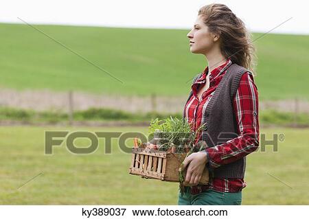 Woman holding a basket of vegetables in a farm View Large Photo Image Stock Photo - Woman holding a basket of vegetables in a farm. Fotosearch