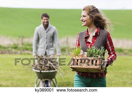 Woman holding a basket of vegetables with her husband collecting firewood View Large Photo Image Stock Image - Woman holding a basket of vegetables with her husband collecting firewood. Fotosearch