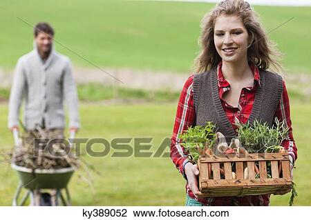 Woman holding a basket of vegetables with her husband collecting firewood View Large Photo Image Stock Image - Woman holding a basket of vegetables with her husband collecting firewood. Fotosearch