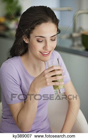 Stock Photo - Woman holding a glass of cold soup and smiling. Fotosearch
