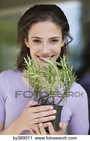 Stock Image - Woman smelling a rosemary plant. Fotosearch