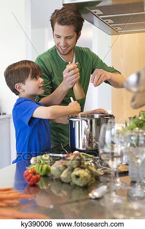 Stock Photograph - Boy assisting his father in the kitchen. Fotosearch