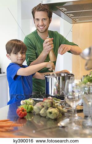 Boy assisting his father in the kitchen View Large Photo Image Stock Photograph - Boy assisting his father in the kitchen. Fotosearch