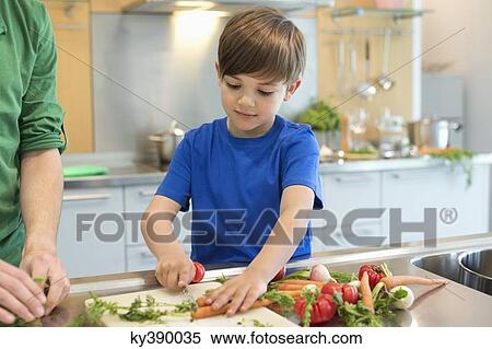 Boy cutting vegetables in the kitchen View Large Photo Image Stock Photography - Boy cutting vegetables in the kitchen. Fotosearch