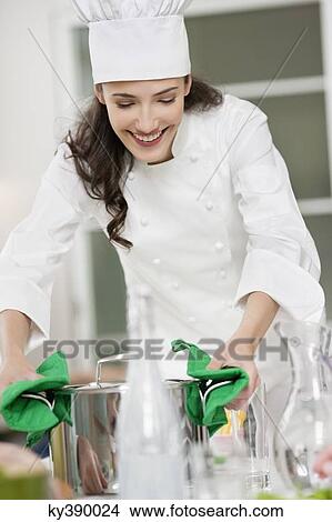 Female chef placing a saucepan on a dining table View Large Photo Image Picture - Female chef placing a saucepan on a dining table. Fotosearch
