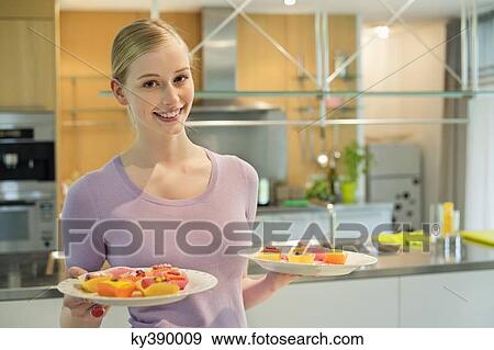 Happy woman holding two plates of cup cakes View Large Photo Image Stock Photo - Happy woman holding two plates of cup cakes. Fotosearch