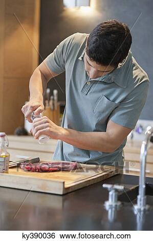 Man sprinkling black pepper on the meat View Large Photo Image Stock Photograph - Man sprinkling black pepper on the meat. Fotosearch