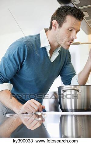 Stock Image - Man tasting food in the kitchen. Fotosearch