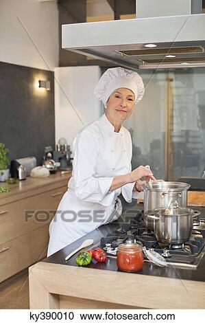 Stock Image - Woman cooking food in the kitchen. Fotosearch