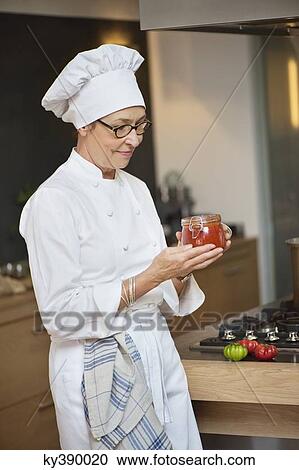 Stock Image - Woman holding a jar of tomato sauce. Fotosearch