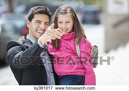 Stock Photo - Man carrying his daughter and pointing with finger. Fotosearch