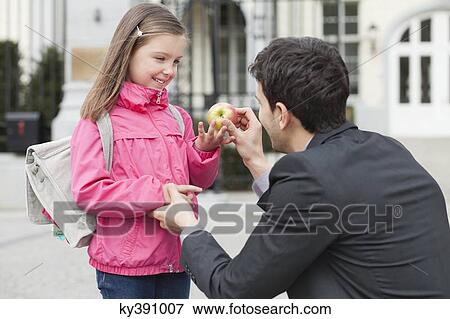 Man giving an apple to his daughter View Large Photo Image Stock Photo - Man giving an apple to his daughter. Fotosearch