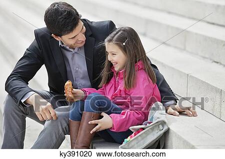 Man sitting with his daughter eating pain au chocolat View Large Photo Image Stock Image - Man sitting with his daughter eating pain au chocolat. Fotosearch