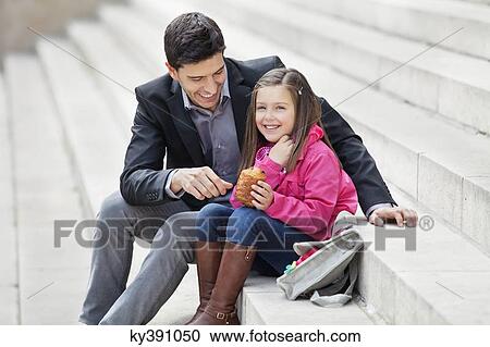 Man sitting with his daughter eating pain au chocolat View Large Photo Image Stock Image - Man sitting with his daughter eating pain au chocolat. Fotosearch