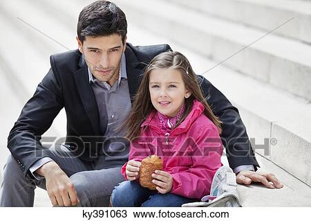 Man sitting with his daughter eating pain au chocolat View Large Photo Image Stock Image - Man sitting with his daughter eating pain au chocolat. Fotosearch